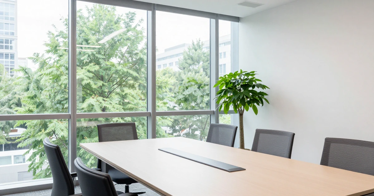 Oficina moderna y minimalista con mesa de juntas, sillas ergonómicas, planta decorativa y ventanales con vista a la ciudad